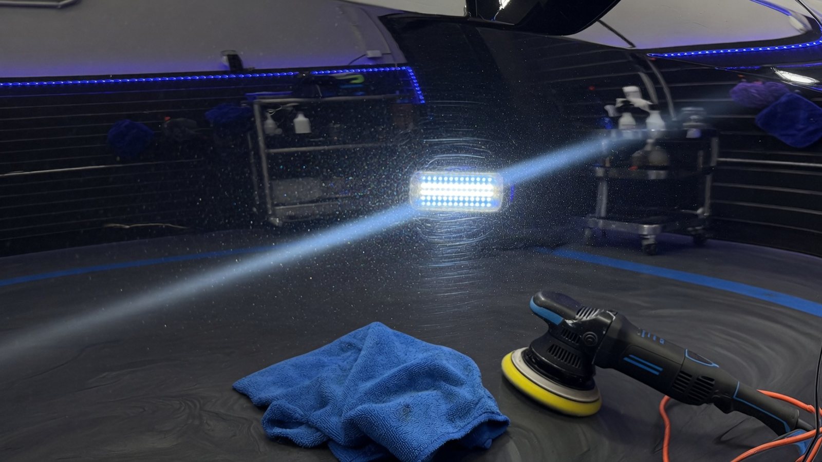 Polished vehicle paint under inspection light in a detailing bay